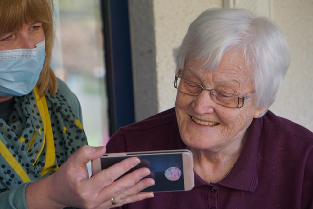 אישה מראה לקשישה פלאפון
